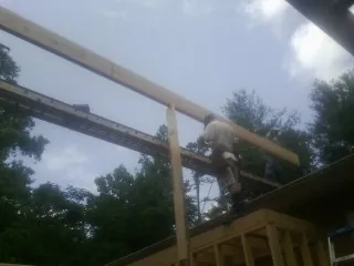 Carpenter setting a ridge beam over a new addition frame — Ice Dam Removal by Roofing Brothers in Horntown