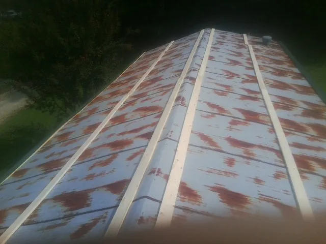Rusted metal roof panels with new wood purlins before replacement — Storm Damage Roof Repair in Horntown by Roofing Brothers
