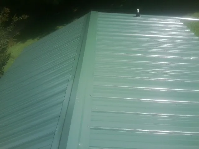 New green metal panels meeting at the ridge of a roof — Flat Roof Repair work by our crew in Horntown