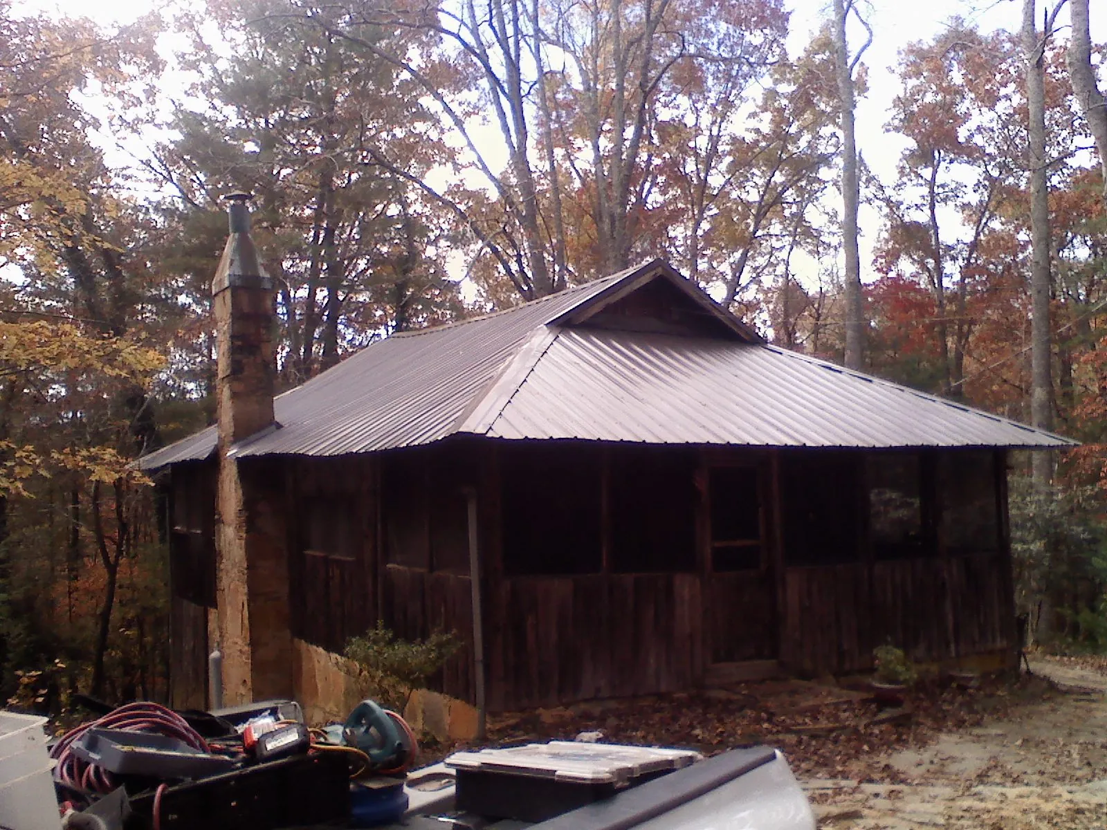 Brown metal hip roof on an old cabin with a stone chimney in Horntown