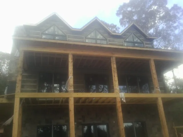 Dormers and porch framing on a large log home under construction — Roof Coating work by our crew in Horntown