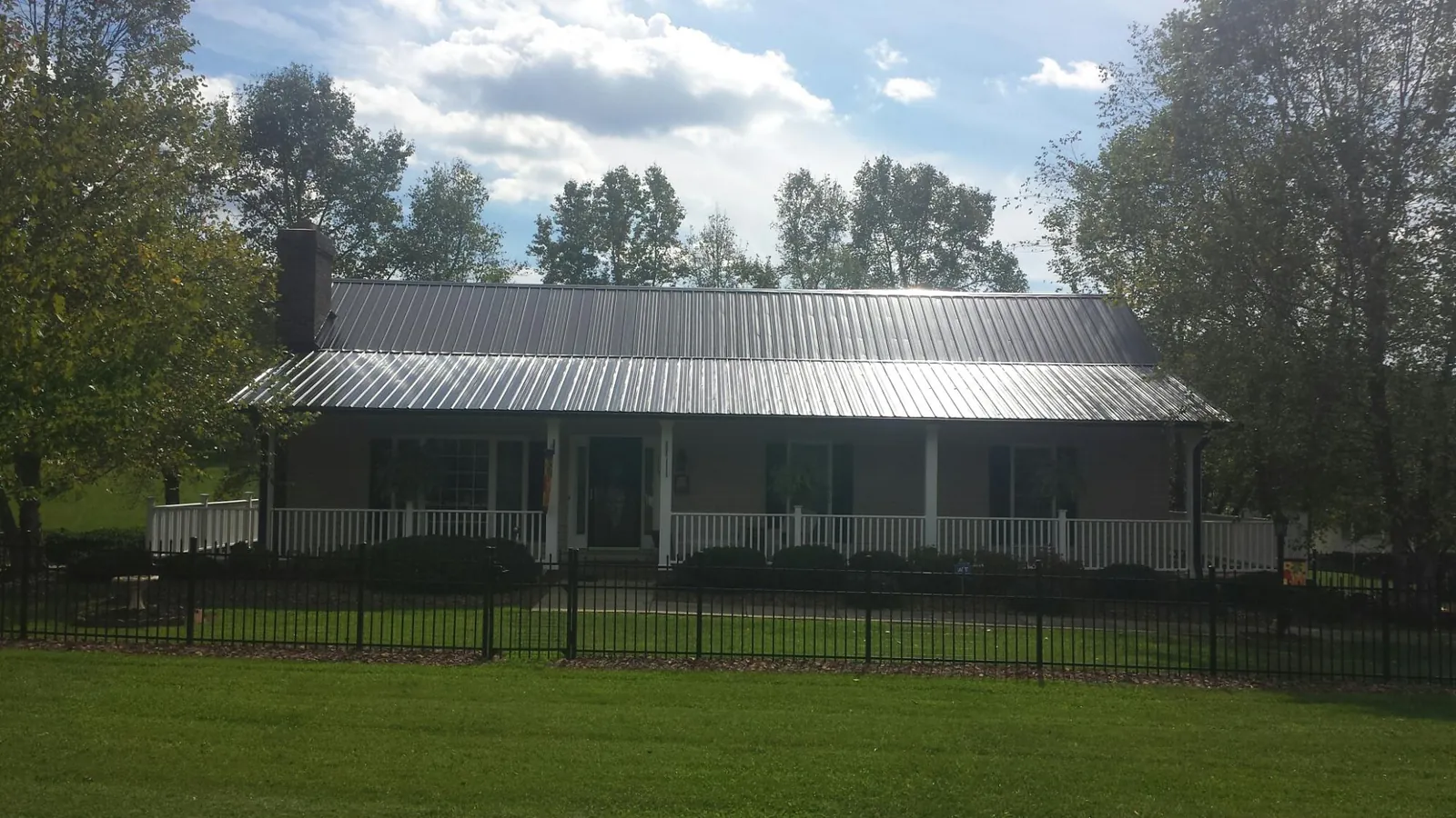 Gray metal roof on a brick ranch with a full width front porch — Gutter Guard Installation work by our crew in Horntown