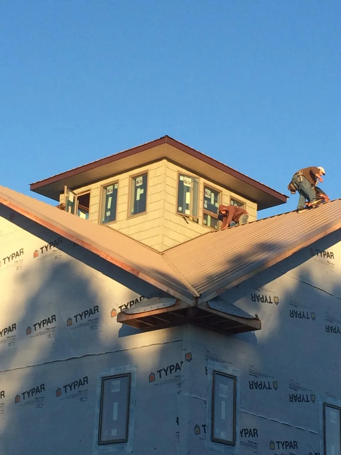 Roofers working around a rooftop cupola on a new metal roof at sunset — Roof Waterproofing in Horntown by Roofing Brothers
